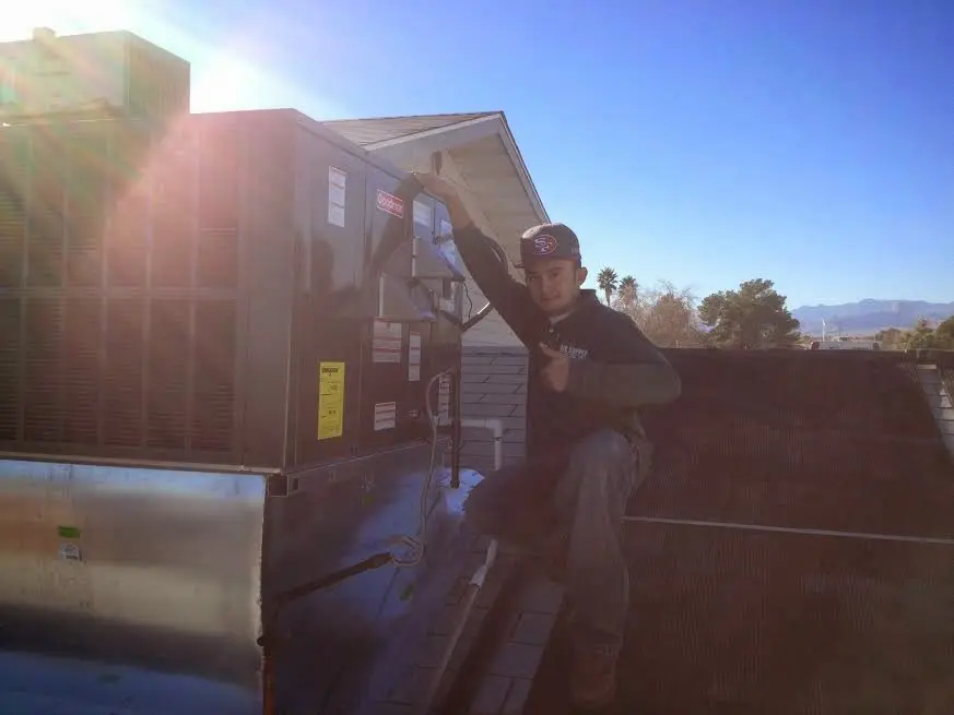 HVAC technician performing Air Duct Cleaning on a rooftop unit in Groves