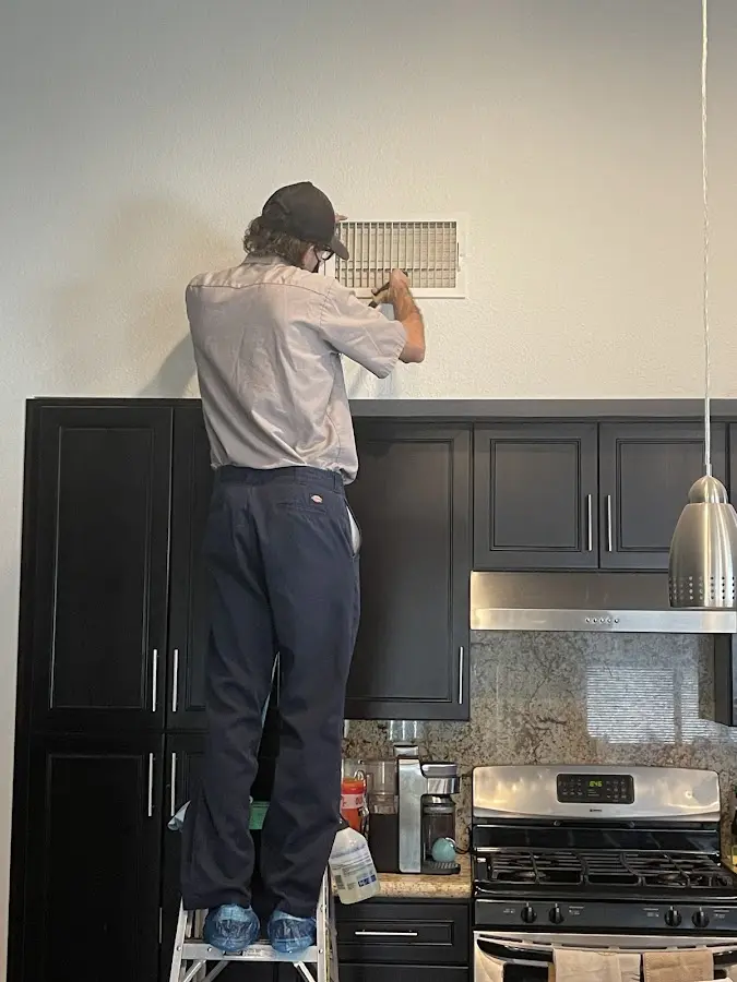 Technician inspecting an air vent during HVAC service in Groves